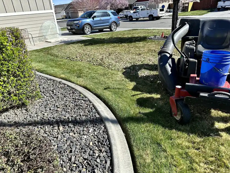 Poured concrete curbing between a fresh lawn and a grey river rock bed