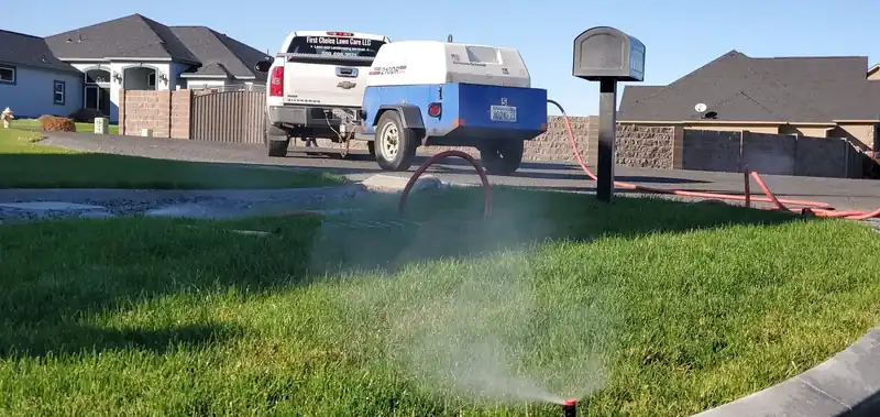 First Choice blowing out a sprinkler system, the compressor trailer hitched to the truck at the curb